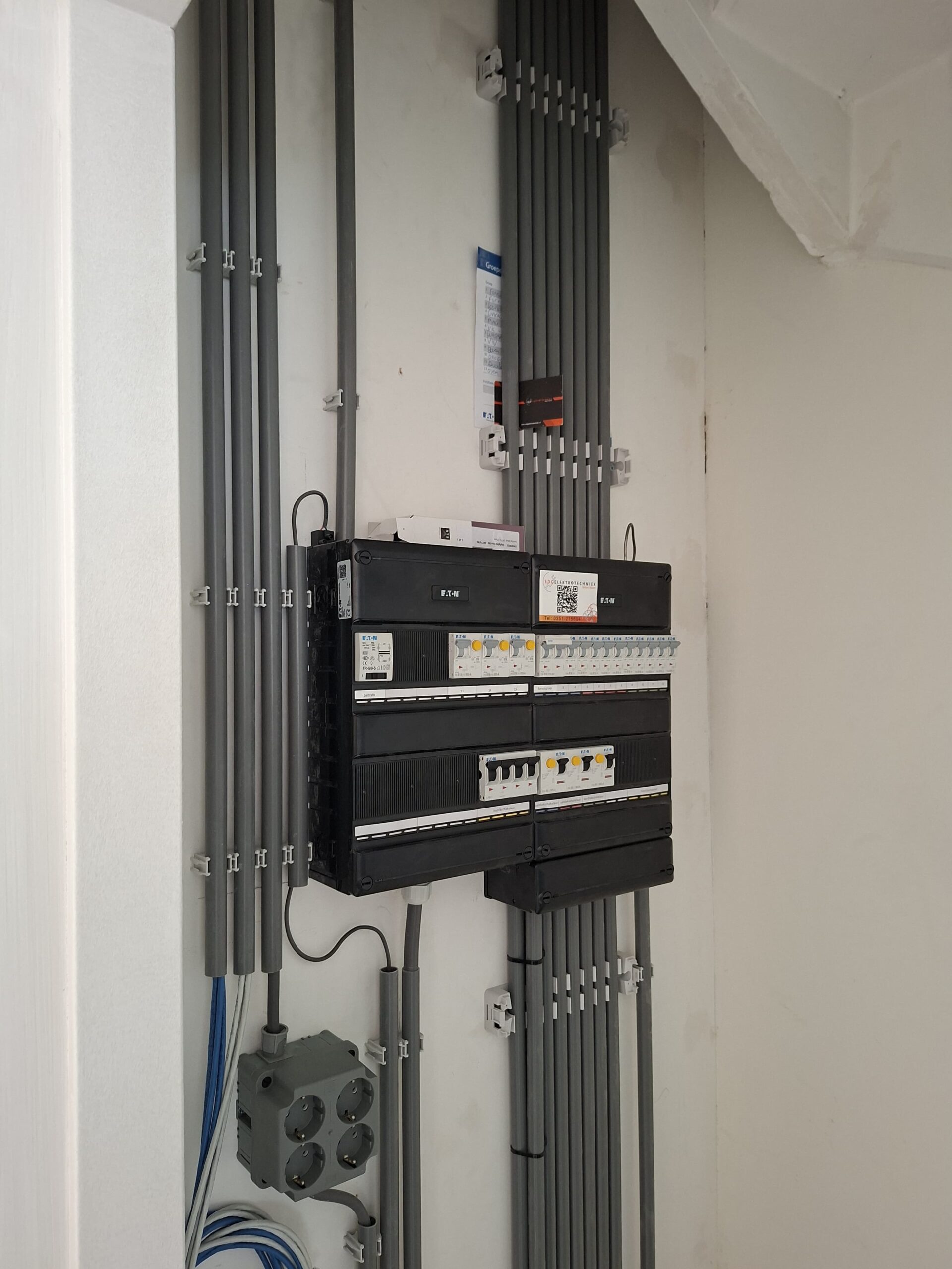 Elektrische meterkast van Eaton met groepenzekeringen, kabelgoten en aansluitdoos gemonteerd aan een muur