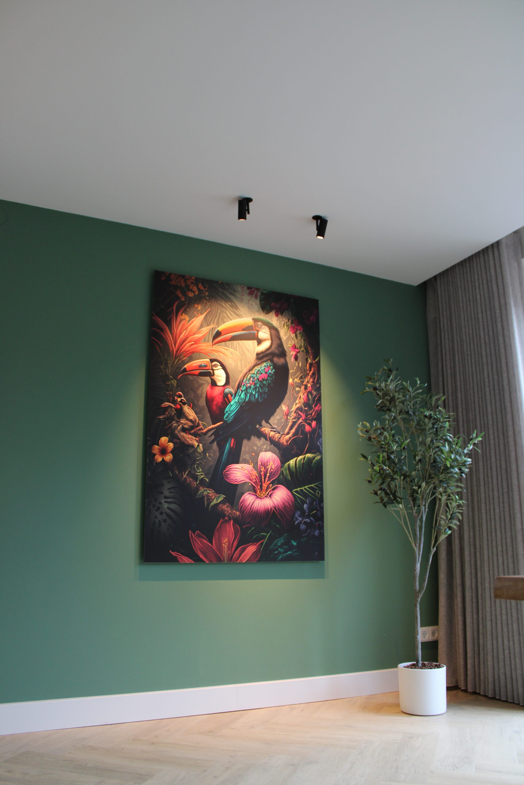Groot canvas met kleurrijke toekannen tussen tropische bloemen en planten, hangend aan een groene muur in een woonkamer